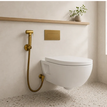 Douchette WC dorée avec flexible installée près d’une toilette suspendue