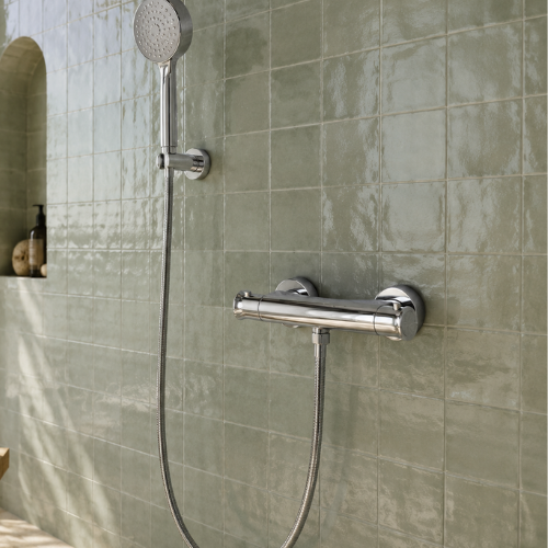 Mitigeur de douche chromé installé sur un mur en carreaux