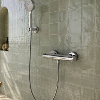 Mitigeur de douche chromé installé sur un mur en carreaux