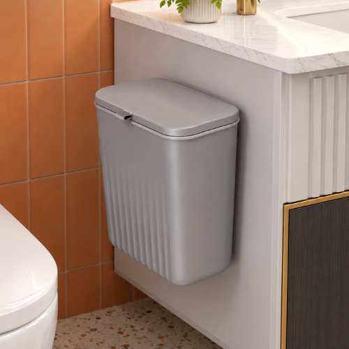 Poubelle grise compacte installée sur le côté d’un meuble lavabo