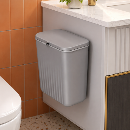 Poubelle grise compacte installée sur le côté d’un meuble lavabo