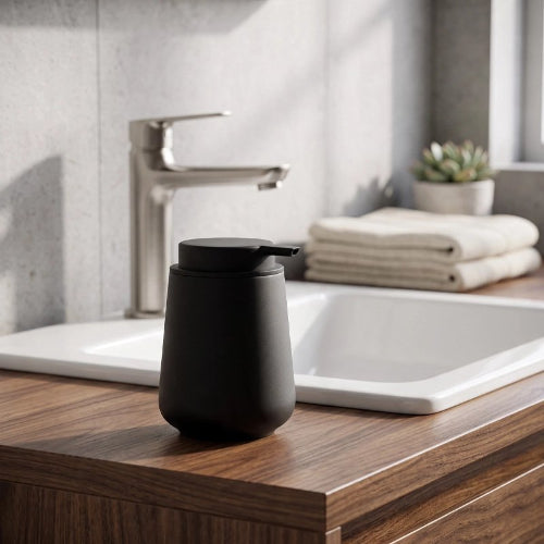 Distributeur de savon noir mat posé sur un meuble lavabo