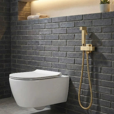 douchette-wc-de-couleur-or-brossé sur mur de brique 