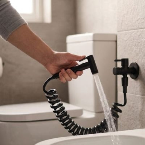 Douchette WC noire utilisée pour l’hygiène intime sur les toilettes