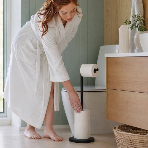 Femme en peignoir utilisant un porte-papier toilette sur pied