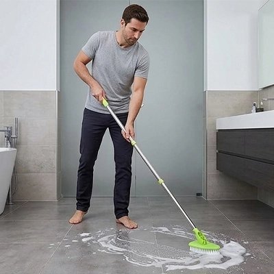 ​Femme utilisant un balai-brosse télescopique pour nettoyer le sol