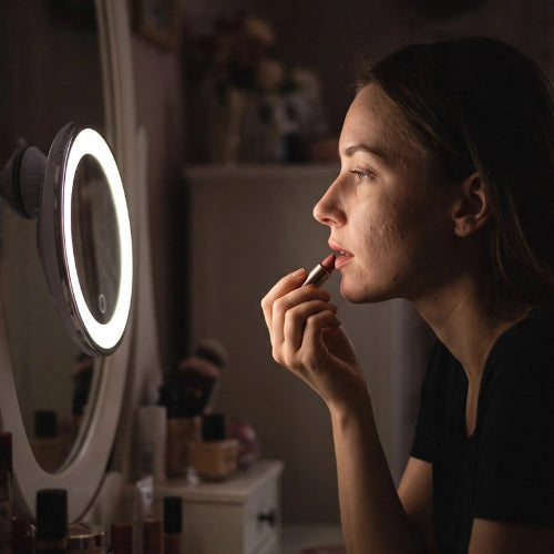 Femme utilisant un miroir grossissant lumineux pour se maquiller