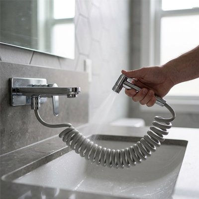 Flexible gris extensible pour douchette WC utilisé près d’un lavabo