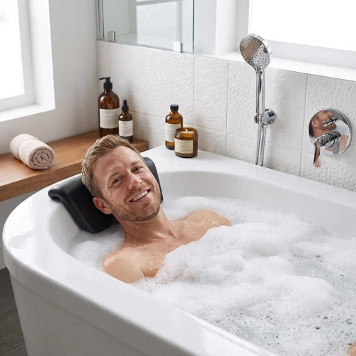 Homme dans un bain moussant, la tête appuyée sur un coussin