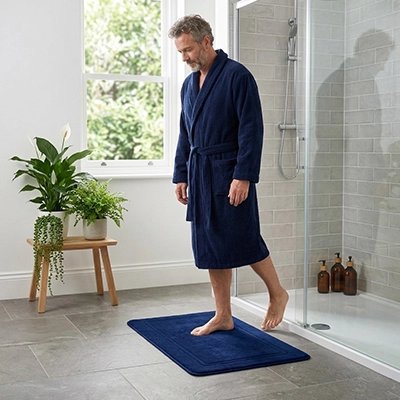 Homme debout sur un tapis de bain bleu moelleux et antidérapant