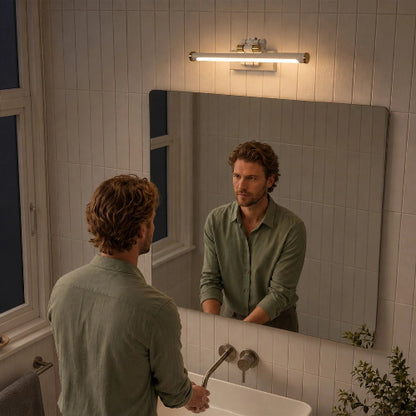 Homme devant un miroir rectangulaire surmonté d’une applique murale LED