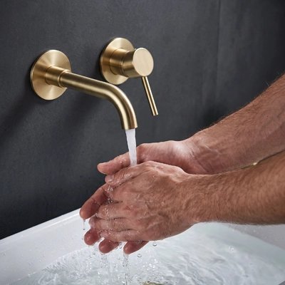 Lavage des mains sous un robinet mural en laiton brossé