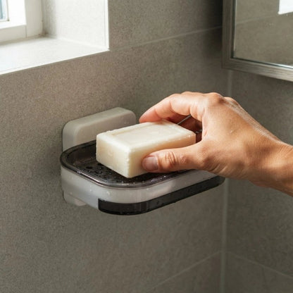Main déposant un savon blanc dans un porte-savon mural