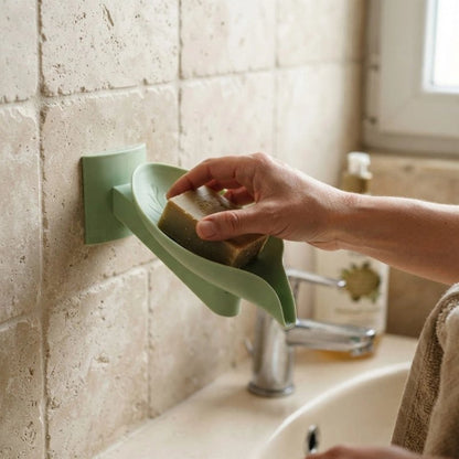 Main déposant un savon dans un porte-savon mural vert