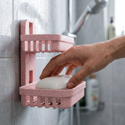 Main prenant un savon dans un porte-savon mural rose