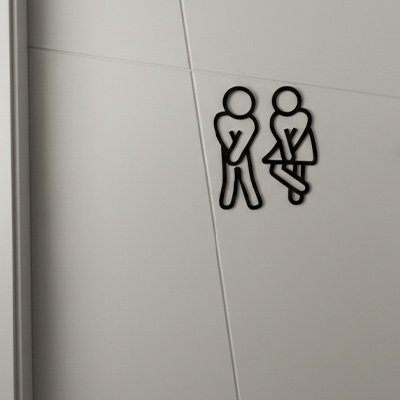 Panneau toilette représentation amusante de personnages en situation d'urgence