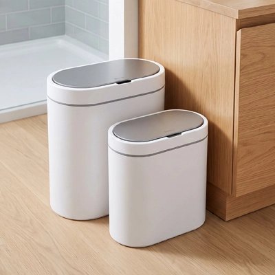 Poubelle compacte blanche placée près des toilettes