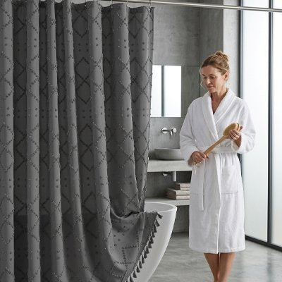 Rideau de douche gris avec pompons décoratifs sur le bord 